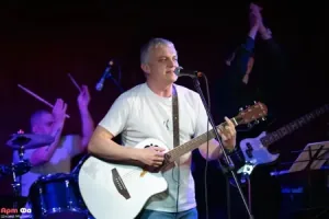 Ученик поёт с акустической гитарой на большом отчётном концерте, апрель 2026